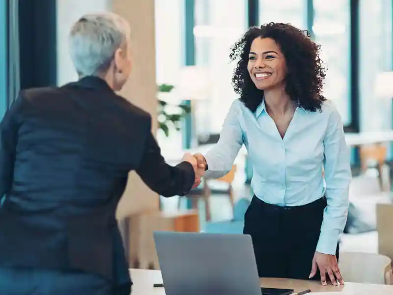 Two business women shaking hands.