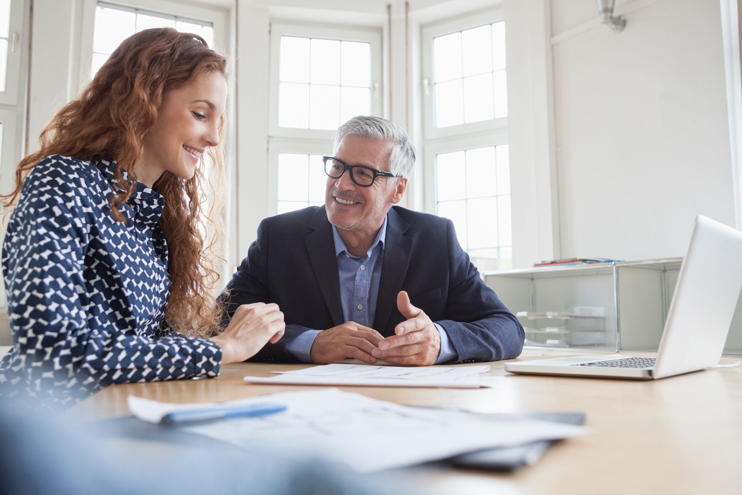 Man and woman smiling at a desk.