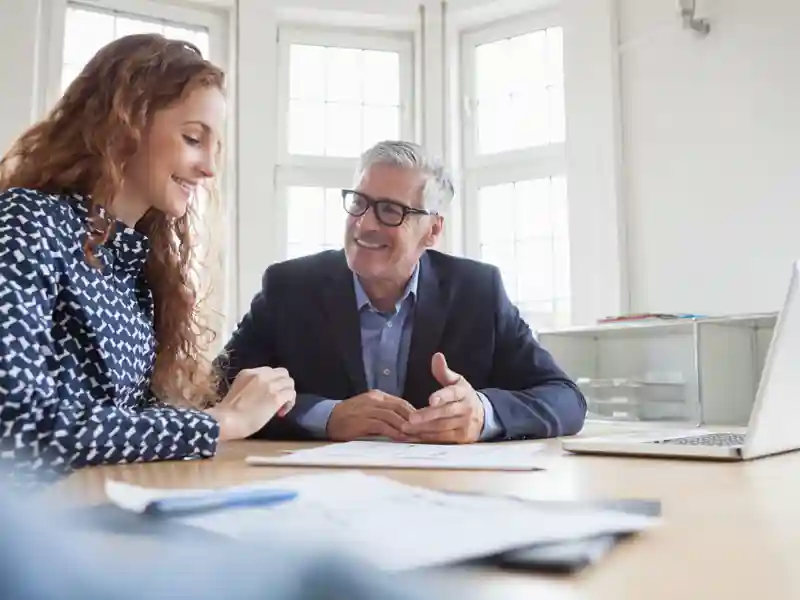 Man and woman smiling at a desk.